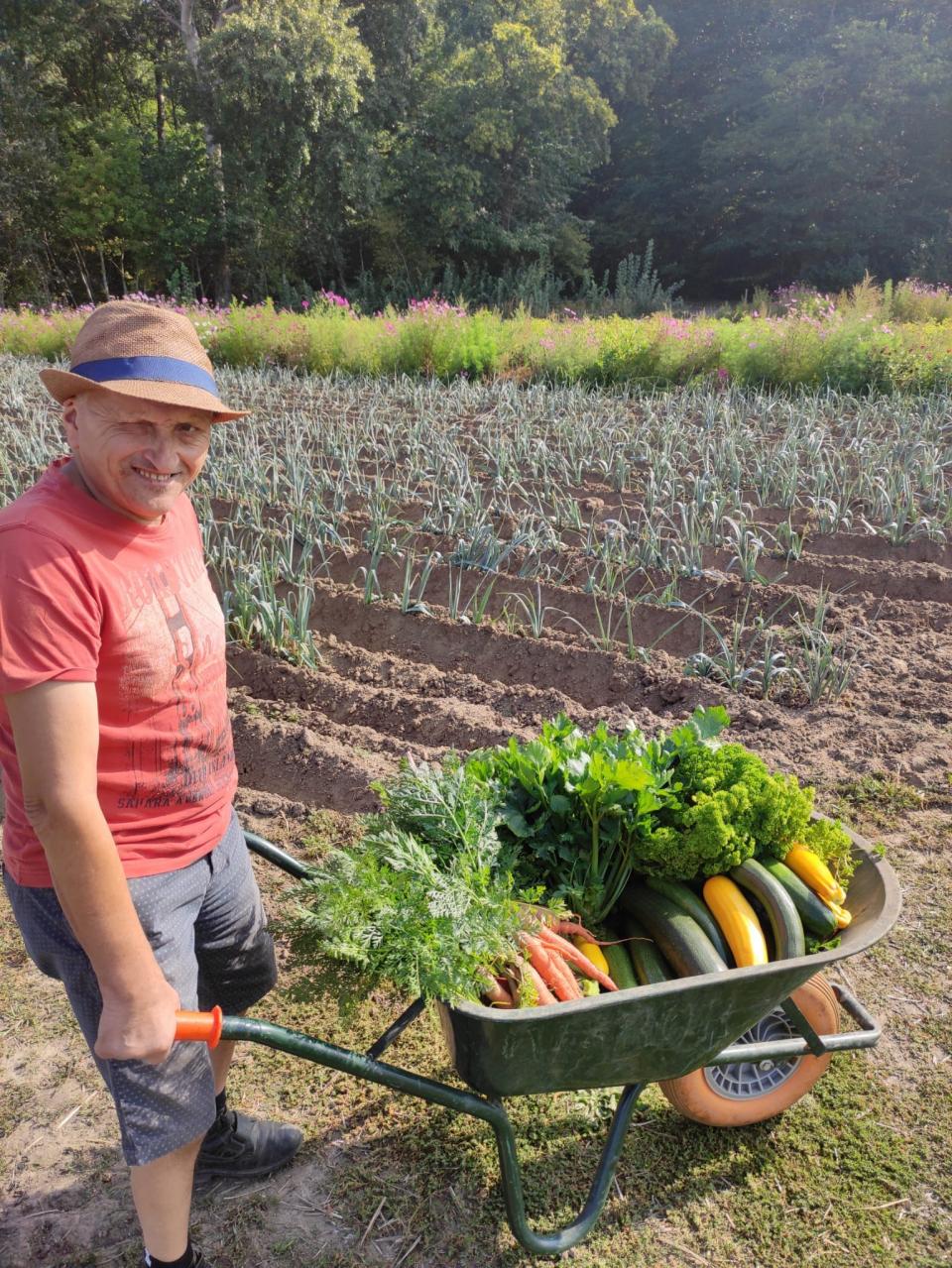 Man met oogst in moestuin.